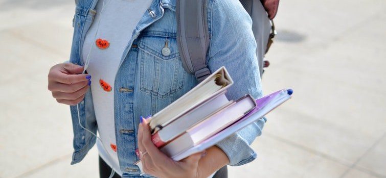A woman carrying a stack of books