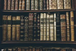 Antique leather-bound books stacked on a wooden shelf