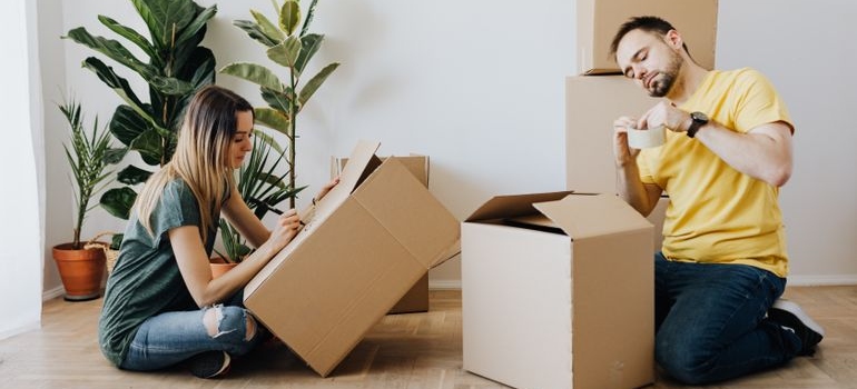 A couple labeling moving boxes by room before a move