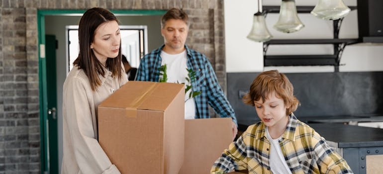 A family carrying moving boxes into their new home after a move to Oxford