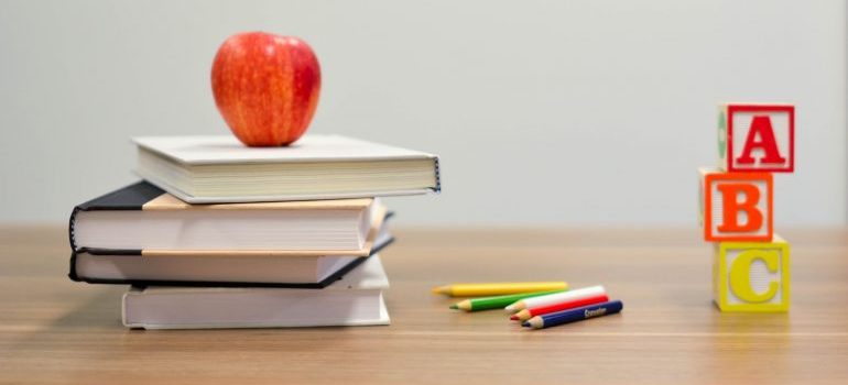 An apple, school books and toy cubes