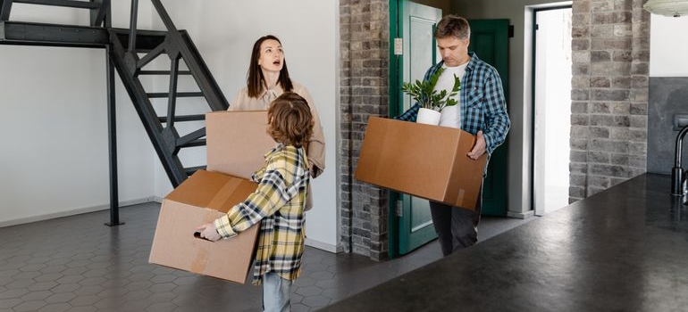 A family carrying moving boxes into their new home