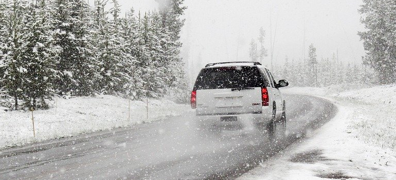 SUV driving on a snow-covered mountain road during a winter storm