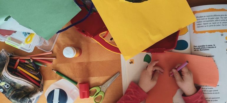 a child coloring and cutting paper shapes
