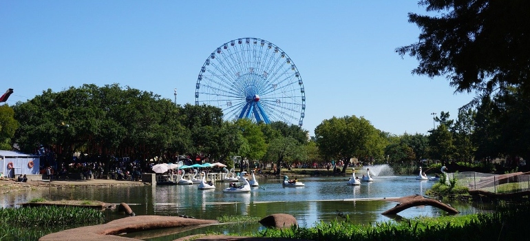 Ferris wheel and lagoon with swan paddle boats at Fair Park, a Dallas landmark for people moving from Memphis to Dallas