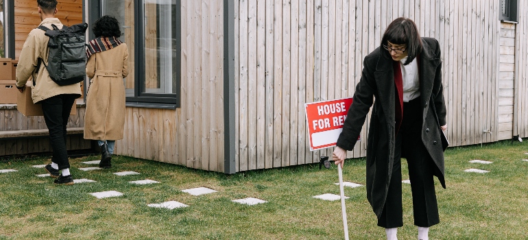A real estate agent removing a for sale sign after selling a home to a couple