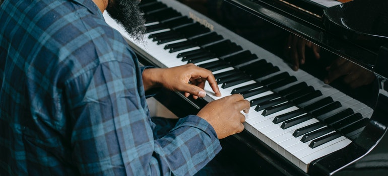 A bearded musician playing the piano after relocation