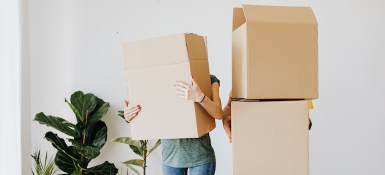 Two people holding cardboard packing boxes