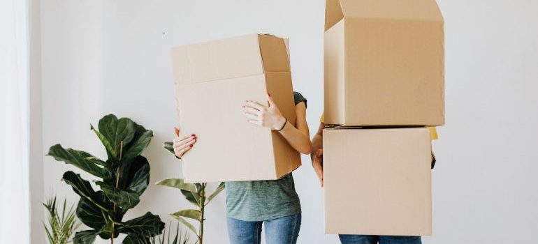 Two people holding a sealed cardboard moving box