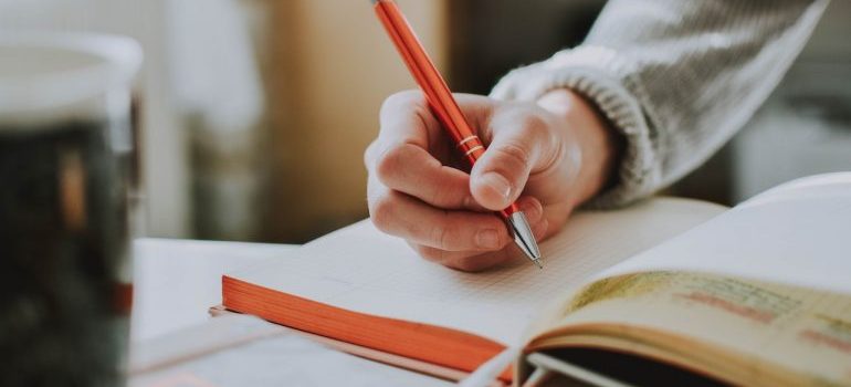 A person writing a checklist in a notebook while planning a move from Texas to Tennessee