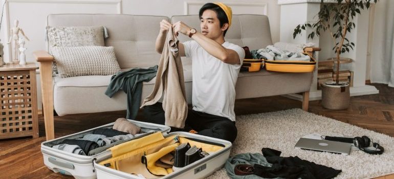 A man packing clothes into a suitcase before moving from Texas to Tennessee