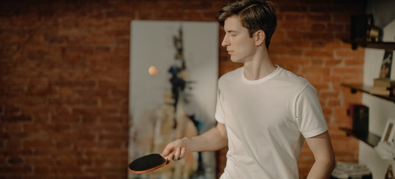 A man playing ping pong on his own at home