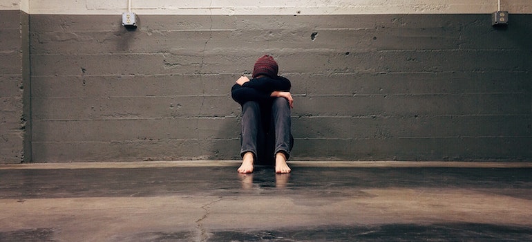 A man sitting alone on the floor with his head down, feeling the anxiety about moving house