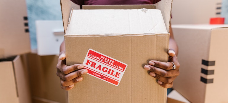 A man carrying a moving box of fragile items