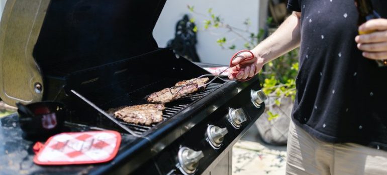 A man cooking on the grill before relocating your backyard grill