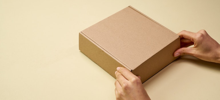A man holding a moving box while packing electronics
