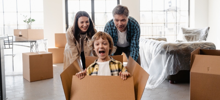 A smiling family sitting among moving boxes in their new home
