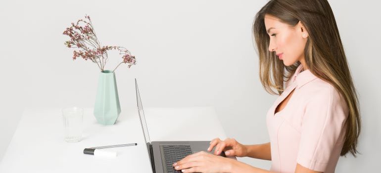 A woman typing on a laptop while comparing school districts before moving from Lakewood to Parker