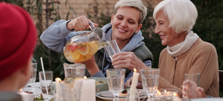 Younger woman pouring juice for an older woman at a table at home