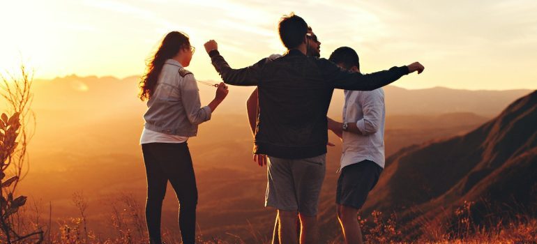 young adults standing at top of mountain in one of the the best Colorado cities for young adults