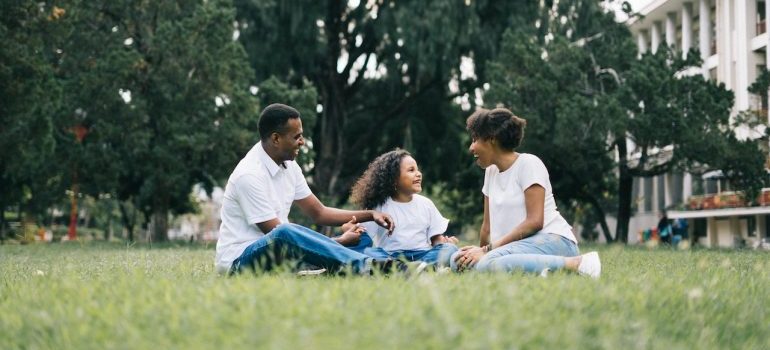 happy family sitting on grass and talking about the real cost of living: Mississippi vs Texas