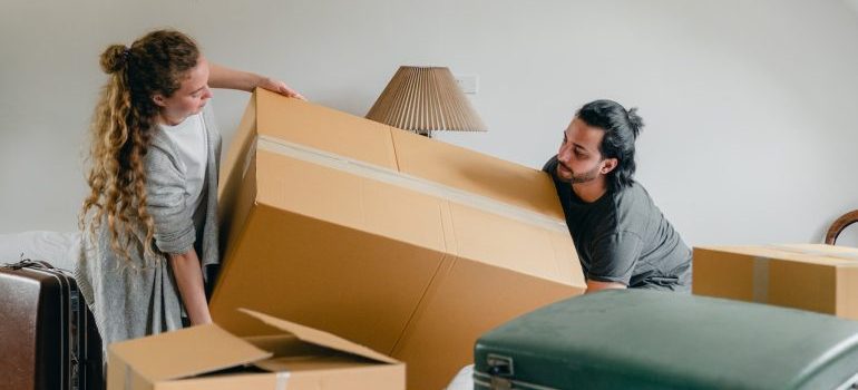 A couple carrying a large moving box into their new home