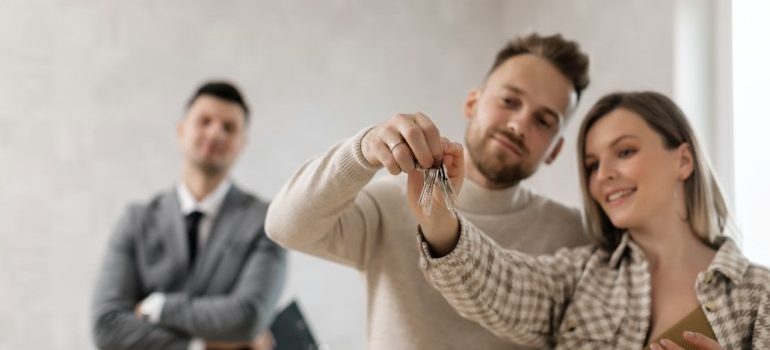 a couple holding aa key and a real estate agent behind them