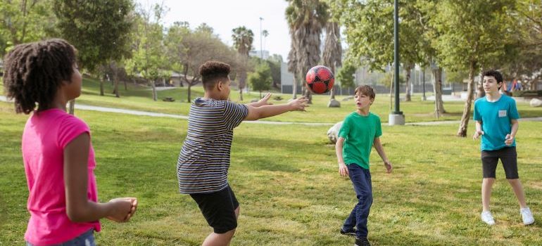 Children playing football on the grass in a town park in Atoka