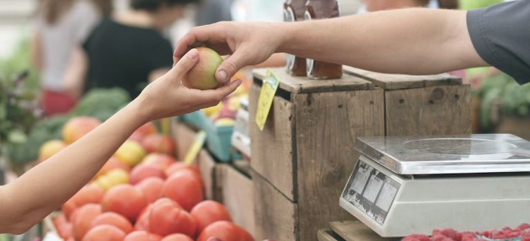 Someone giving fruit to another person at the Farmers market in Cordova, one of the top-rated spots for expats in TN