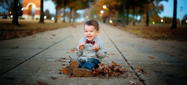 A child playing with fallen autumn leaves in a park