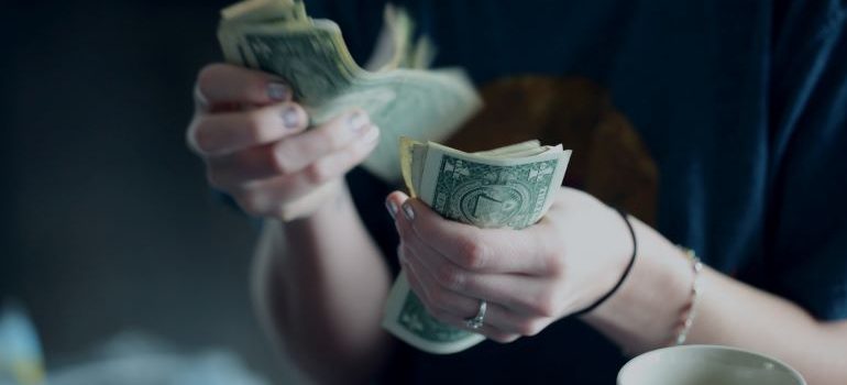 A person counting dollar bills while budgeting for a move to Brighton