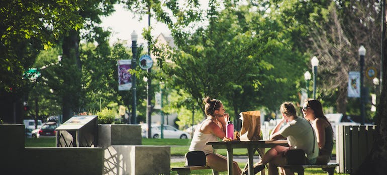 Women sitting on a bench in the park discussing the Greenwood Village vs Englewood choice