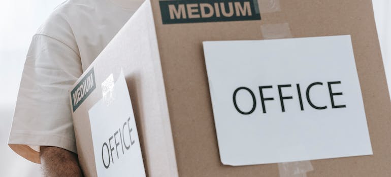 A mover carrying a cardboard box labeled office