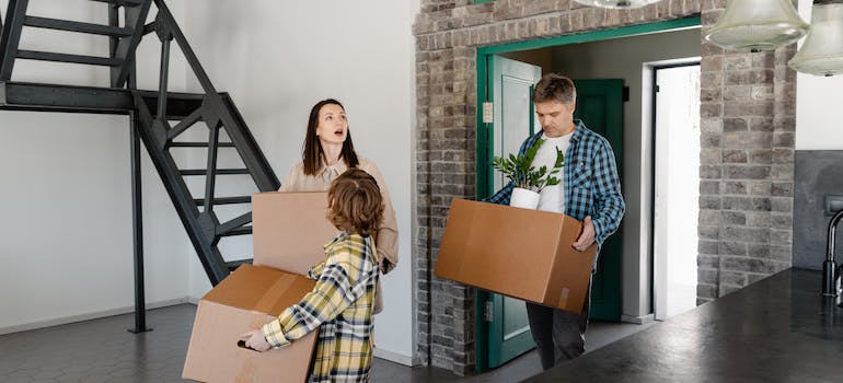 Young parents carrying moving boxes into a home with their child