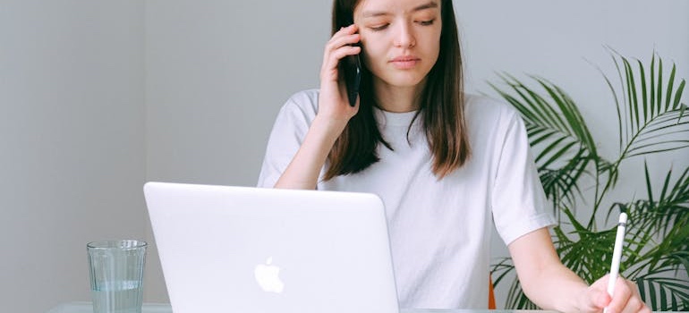 A woman on a phone call booking movers for summer, the busiest time of year to move to Colorado