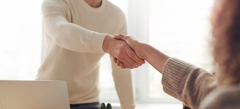 Two people shaking hands across a table after a job interview