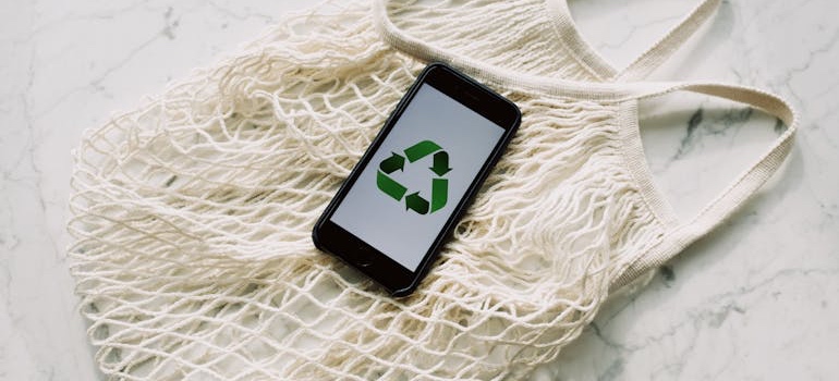 A tote bag with a phone on it that is showing the recycling symbol