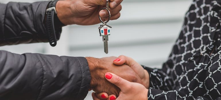 A real estate agent handing house keys to someone moving out of the family home