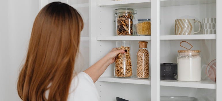 A woman organizing jars and food containers in her pantry