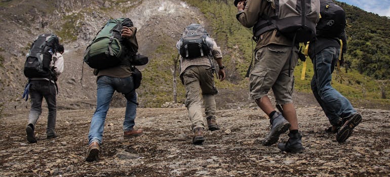 Group of hikers with backpacks walking up a rocky slope