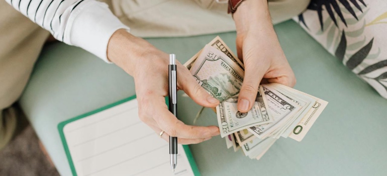 Person counting dollar bills over a desk