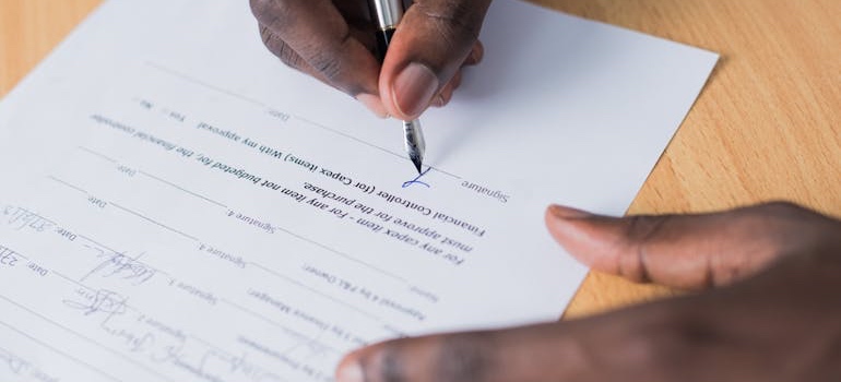 A person signing a rental contract, a key step in a student’s guide to off campus housing
