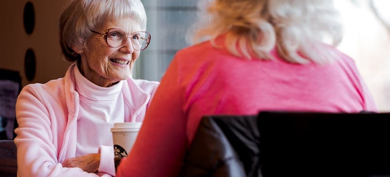 Group of senior friends talking over coffee at a coffee shop table
