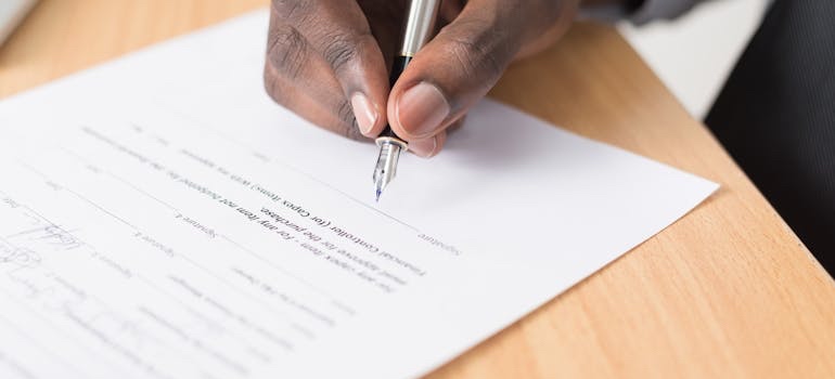 A person signing a document at a desk