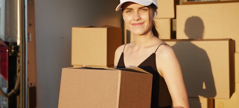 Mover in a work uniform standing next to moving boxes
