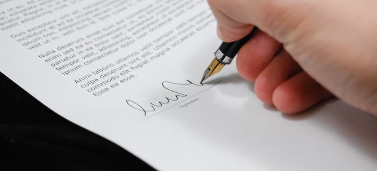 Person signing a moving contract with a pen
