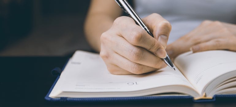 A person writing an inventory list to prepare for partial moves and minimalist relocations