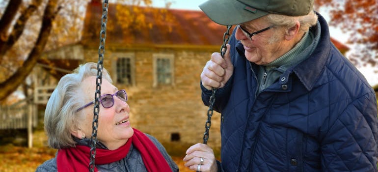 Three senior friends laughing together on a park bench