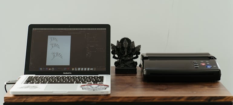 A printer connected to a laptop on an office desk