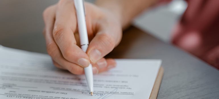 A person signing a contract for an apartment in the perfect Denver neighborhood based on your commute